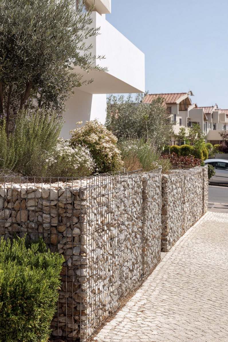 Modern stone and wire mesh fence with greenery