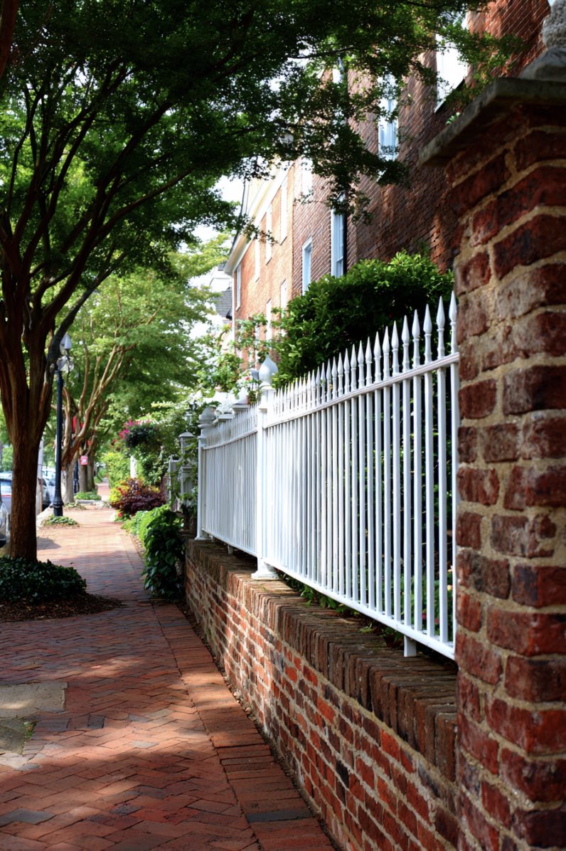 Red brick fence with white metal railings in classic style